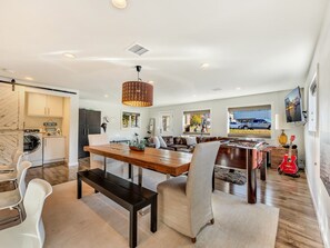 A modern kitchen with a dining area, a foosball table, and a red guitar.