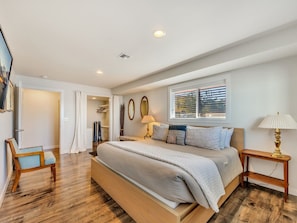 A spacious bedroom with a large bed, bedside lamps, a wardrobe, and a window with blinds. - Riverfront Astoria Condo on Pier, Walk Everywhere (Astoria)