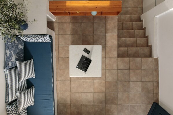 A top-down view of a staircase with a blue sofa and patterned cushions, a white table with a laptop, and a potted plant. - Sunset Beach house with two bedrooms (Stelida)