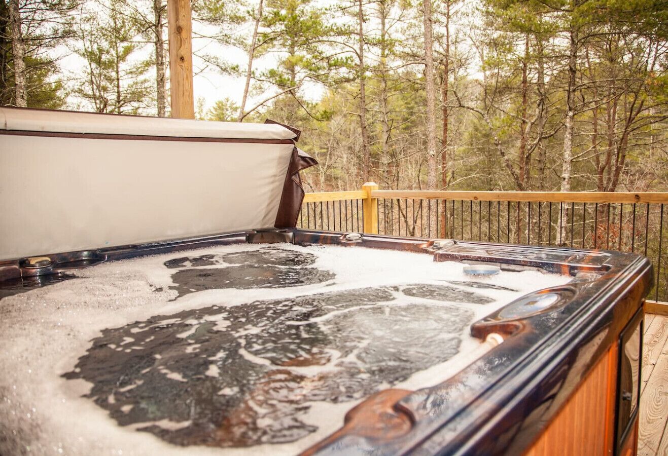 Un bain à remous avec une terrasse en bois et une vue sur une zone boisée.