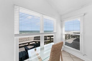 Ein Balkon mit Glastisch und Stühlen, weißen Wänden und Blick auf den Strand.
