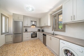 A modern kitchen with stainless steel appliances, white cabinetry, and a granite countertop. - Villa Onera in Vlachata (Vlachata)