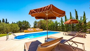 Área da piscina com espreguiçadeiras, guarda-sóis e piscina.
