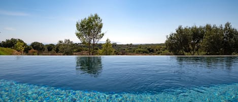 A clear pool with a view of trees and hills in the background.