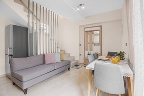 A modern living room with a grey sofa, a dining table with chairs, and a staircase with a railing. - Park and sea view Villa with Private Pool 2 (Chania)
