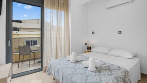 A hotel room with a bed, a window with curtains, an air conditioner, and a view of the outside balcony. - Park and sea view Villa with Private Pool 2 (Chania)