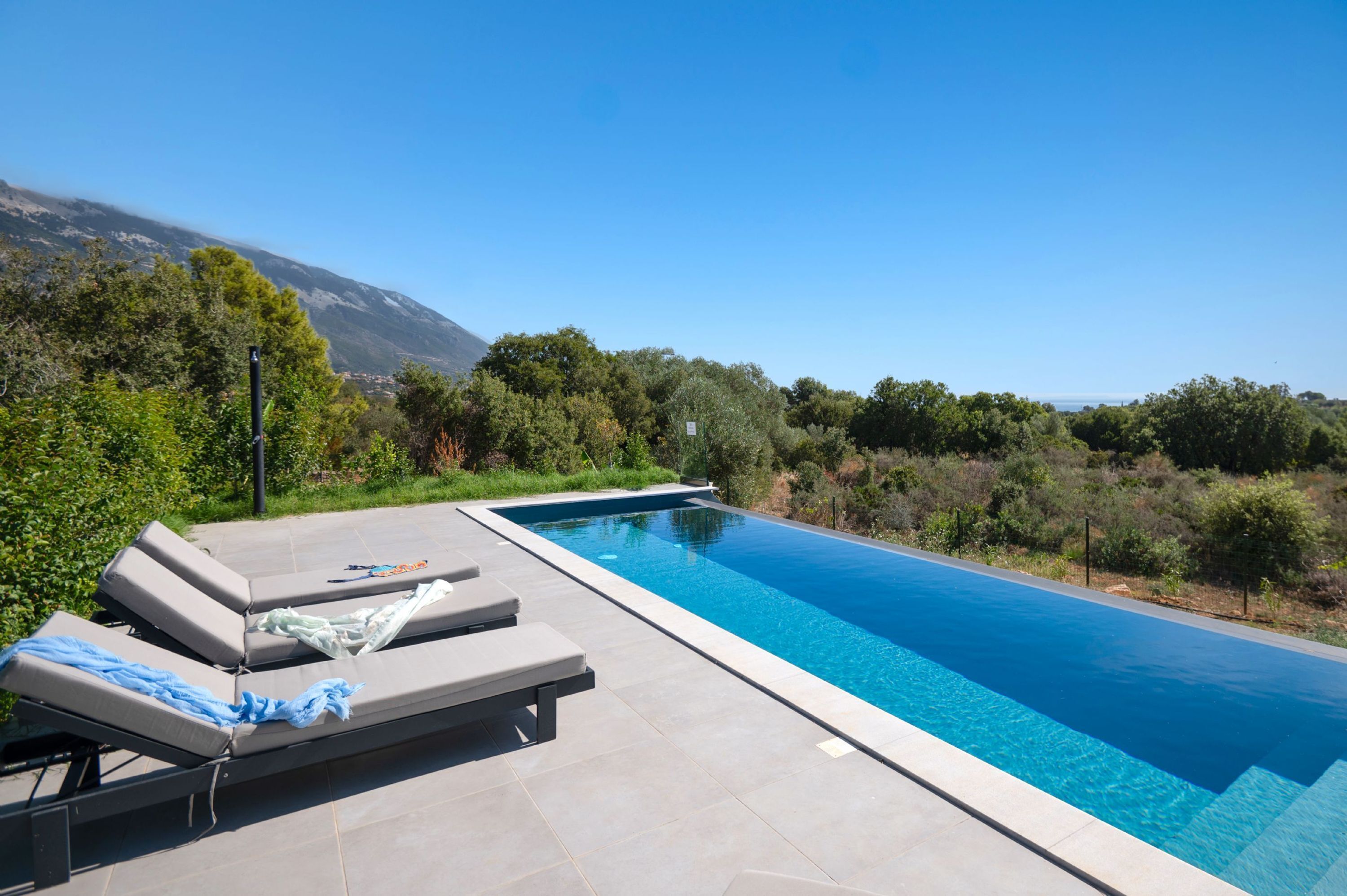 A rectangular swimming pool with a clear blue water surface, surrounded by a tiled deck.