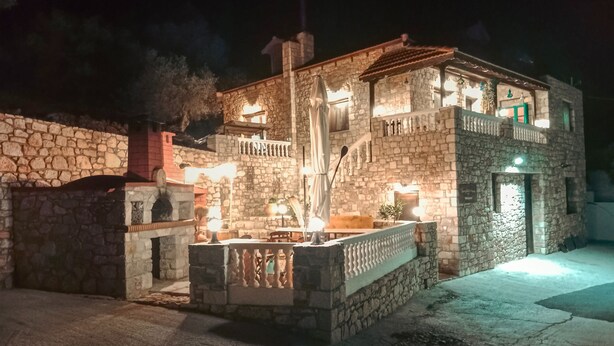 A stone building with a balcony and a staircase, illuminated by exterior lights. - Tsampika's Traditional Stone Cottage in Siana (Siana)