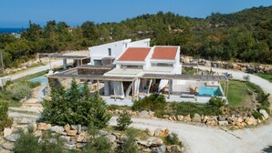 Una villa moderna con diversi livelli, una piscina e vista sul mare.