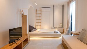 Un bagno moderno con una vasca freestanding, un mobile bagno in legno, una televisione e un'ampia finestra con tende.