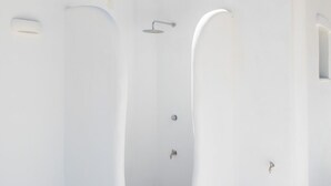 Uma casa de banho moderna e branca, com uma banheira independente, chuveiro e sanita.