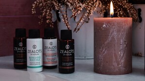 Quatro embalagens de shampoo e leite de corpo refrescantes Zealots of Nature, e uma vela acesa.