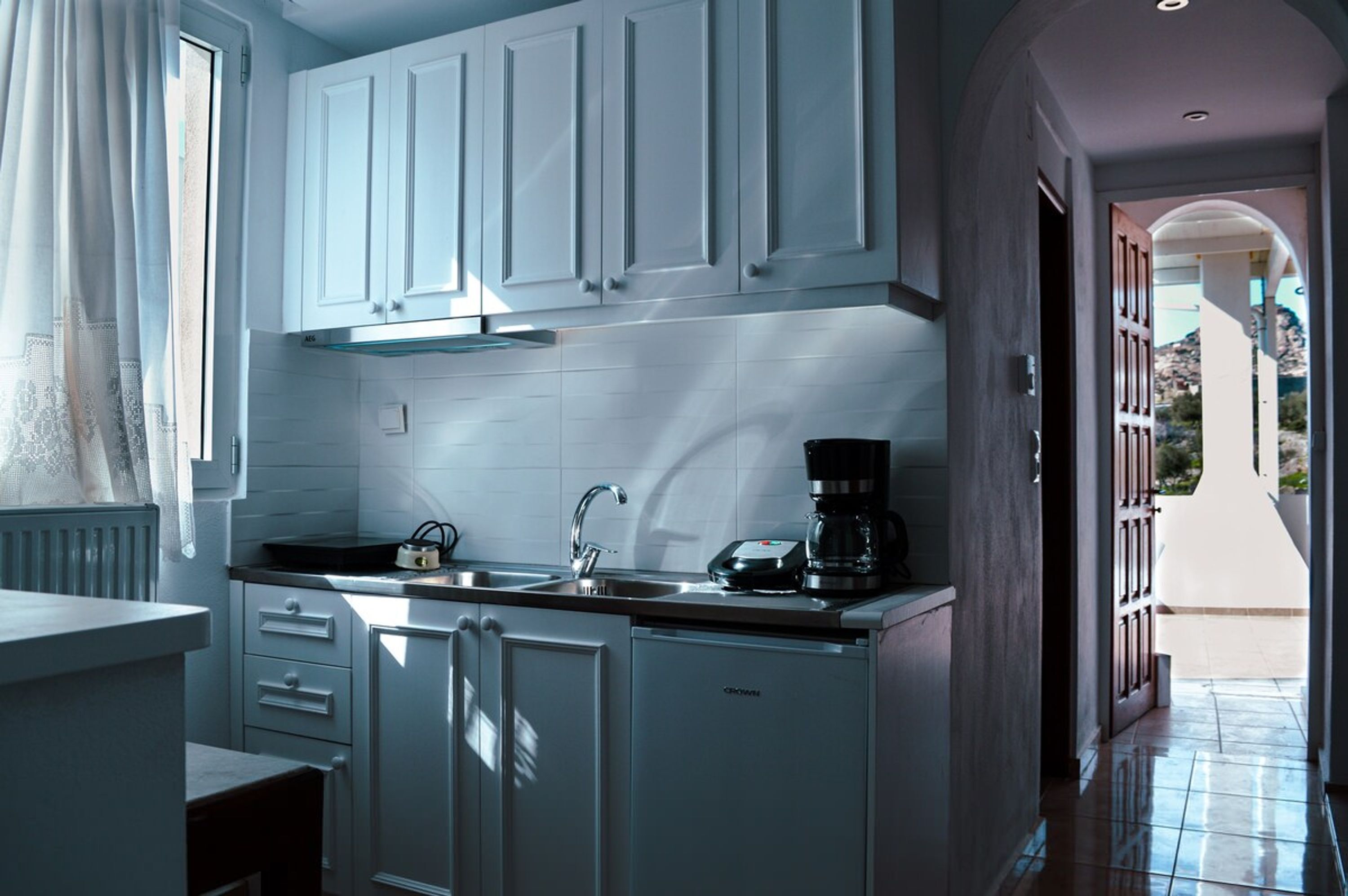 Una cocina moderna con armarios blancos, encimera negra y una cafetera.