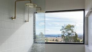 A shower with a view of a landscape through a window. - Barefoot Luxury, Romantic Escapes, Outdoor Bath with a view, Rolling hills (Carlton River)