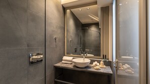 Un baño moderno con un espejo grande, un lavabo sobre encimera y una cabina de ducha de vidrio.