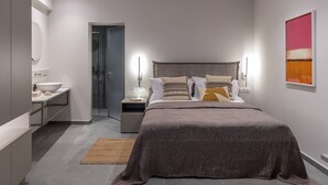 Et moderne soveværelse med en stor seng, sengeborde, et natbord, et spejl og et billede på væggen.