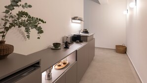 A modern kitchen with a built-in island, a coffee machine, and a hanging plant. - Nyx - by Celestial Suites (Athina)