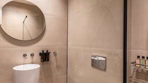 A modern bathroom with a round mirror, a white sink, and a toilet. - Nyx - by Celestial Suites (Athina)