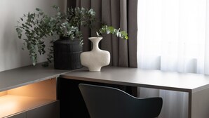 A modern, compact workspace with a desk, chair, and two potted plants. - Nyx - by Celestial Suites (Athina)