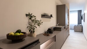 Una cocina moderna con lavavajillas integrado, un cuenco de fruta, una planta en maceta y un botellero.
