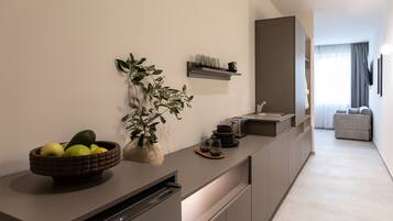A modern kitchen with a built-in dishwasher, a bowl of fruit, a potted plant, and a wine rack.