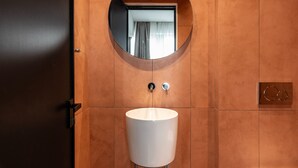 Un baño con un espejo redondo, un lavabo blanco y una puerta.