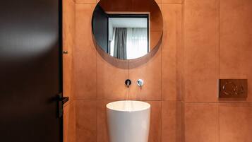 A bathroom with a round mirror, a white sink, and a door.
