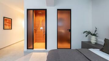 A modern bedroom with a bed, a nightstand, a vase with plants, and a sliding door leading to a shower area.