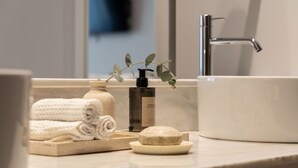 Ein Badezimmer mit weißem Waschbecken, einer Handseifenflasche, einer Seife und ordentlich gefalteten Handtüchern.