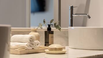 A bathroom with a white sink, a bottle of hand soap, a bar of soap, and neatly folded towels.