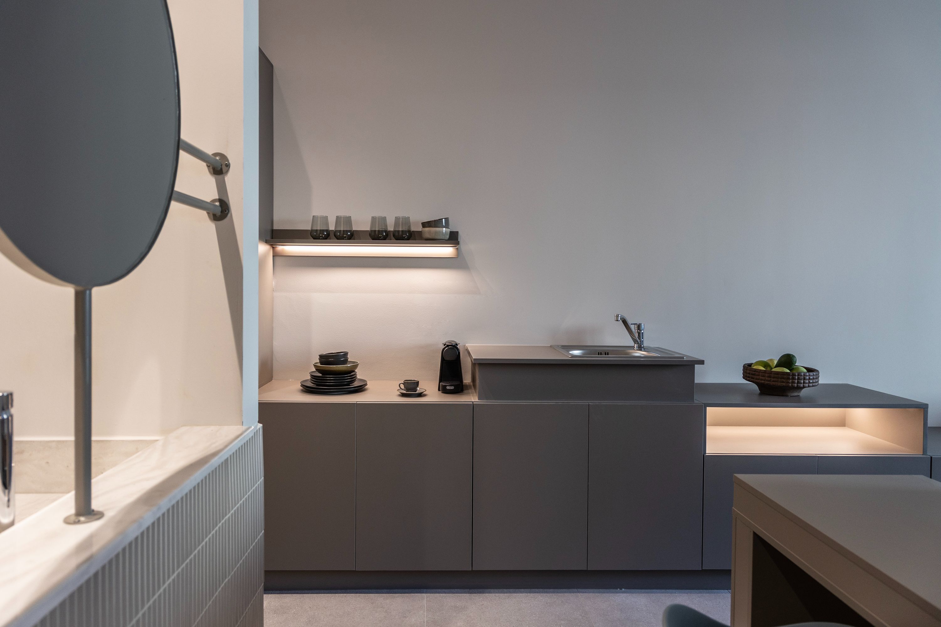 A modern kitchen with a built-in stove, a sink, and a countertop with a coffee maker and a bowl of fruit.