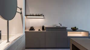 Eine moderne Küche mit Einbauherd, Spüle und einer Arbeitsplatte, auf der ein Kaffeeautomat und eine Obstschale stehen.