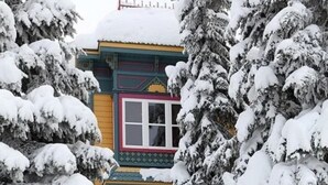 A two-story building with a snow-covered roof and windows, surrounded by snow-laden trees. - Fabulous 5-bedroom house at Silver Star Mountain perfect for family getaways! (Vernon)