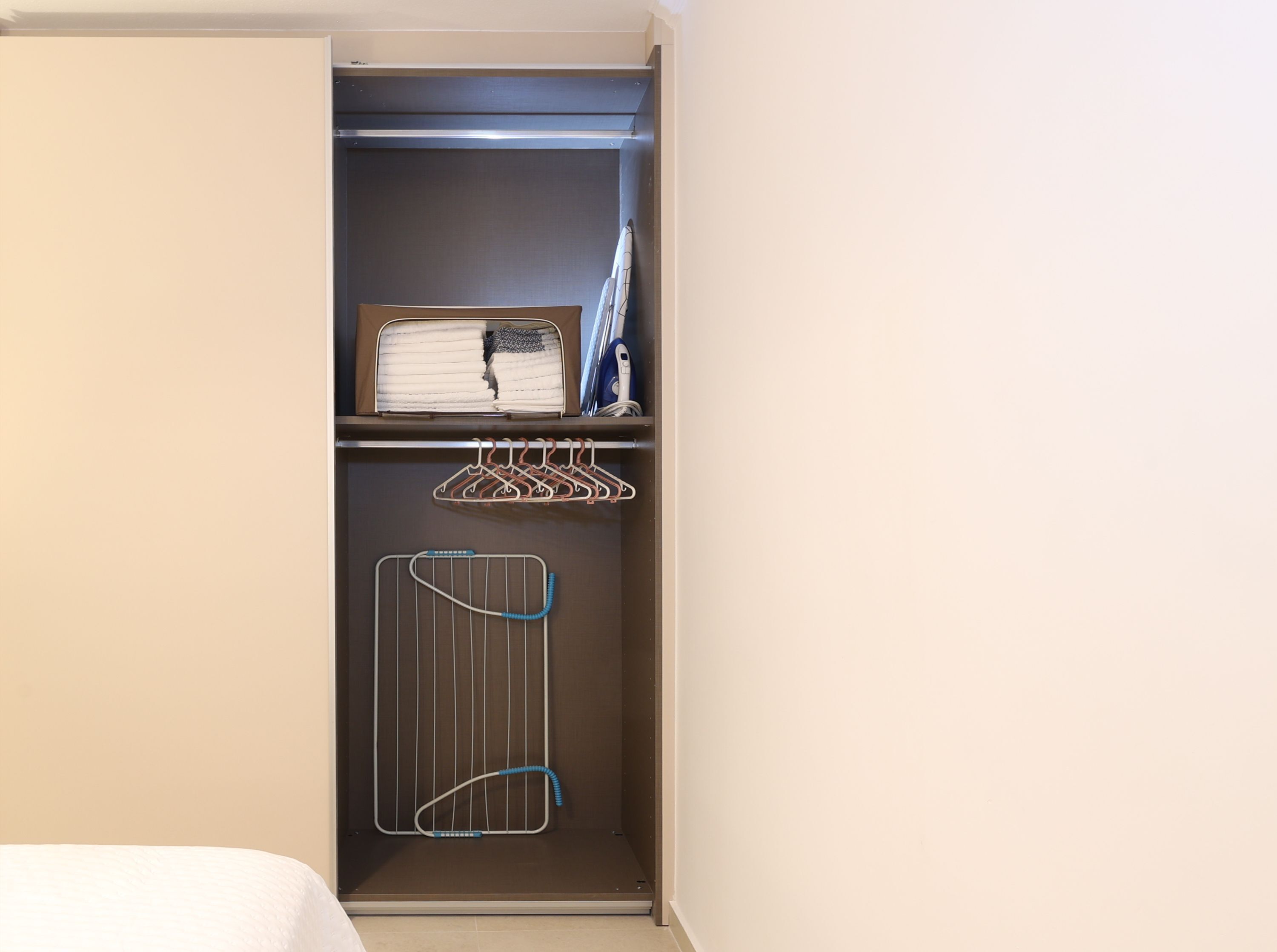 A wardrobe with a hanging organizer, a folded towel, and a metal drying rack.