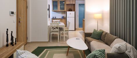 A living room with a sofa, a coffee table, and a dining area with a table and chairs.