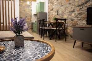 Une pièce avec une table ronde, une plante en pot, un mur en pierre et un téléviseur.