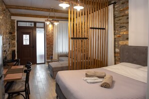 A room with a bed, a wooden partition, a dining area, and a stone wall. - The  Lake House  Angeliki (Kanalia)