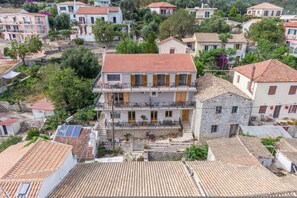 Ein Wohngebäude mit rotem Ziegeldach, einem Balkon mit schwarzer Geländer und einer Stein-Fassade.