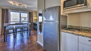 A modern kitchen with stainless steel appliances, a granite countertop, and a dining area with a view.