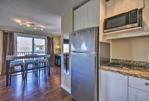 Una cocina moderna con electrodomésticos de acero inoxidable, encimera de granito y comedor con vistas.