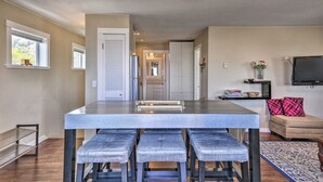 A modern kitchen with a central island, bar stools, and a dining table.