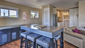 A modern kitchen with a central island, bar stools, and a view of the adjacent living area.