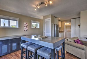 Una cocina moderna con una isla central, taburetes de bar y vistas al área de estar contigua.
