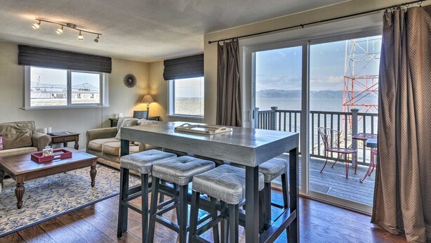 A spacious living area with a large window, a bar area with stools, and a view of the outside.