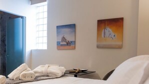 A hotel room with a bed, towels, a desk, and two paintings on the wall. - Trikala Mall Suites 2nd Floor Suite Number 21 (Trikala)