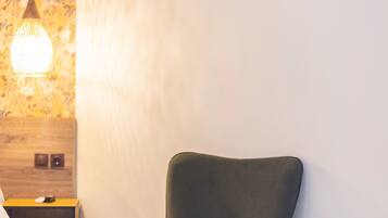 A modern room with a green armchair, a small round table with a candle, and a wall-mounted air conditioner.