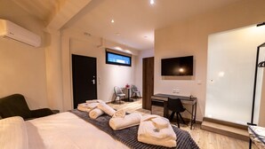 Une chambre d’hôtel équipée d’un lit, d’un bureau, d’une télévision et d’un espace douche.