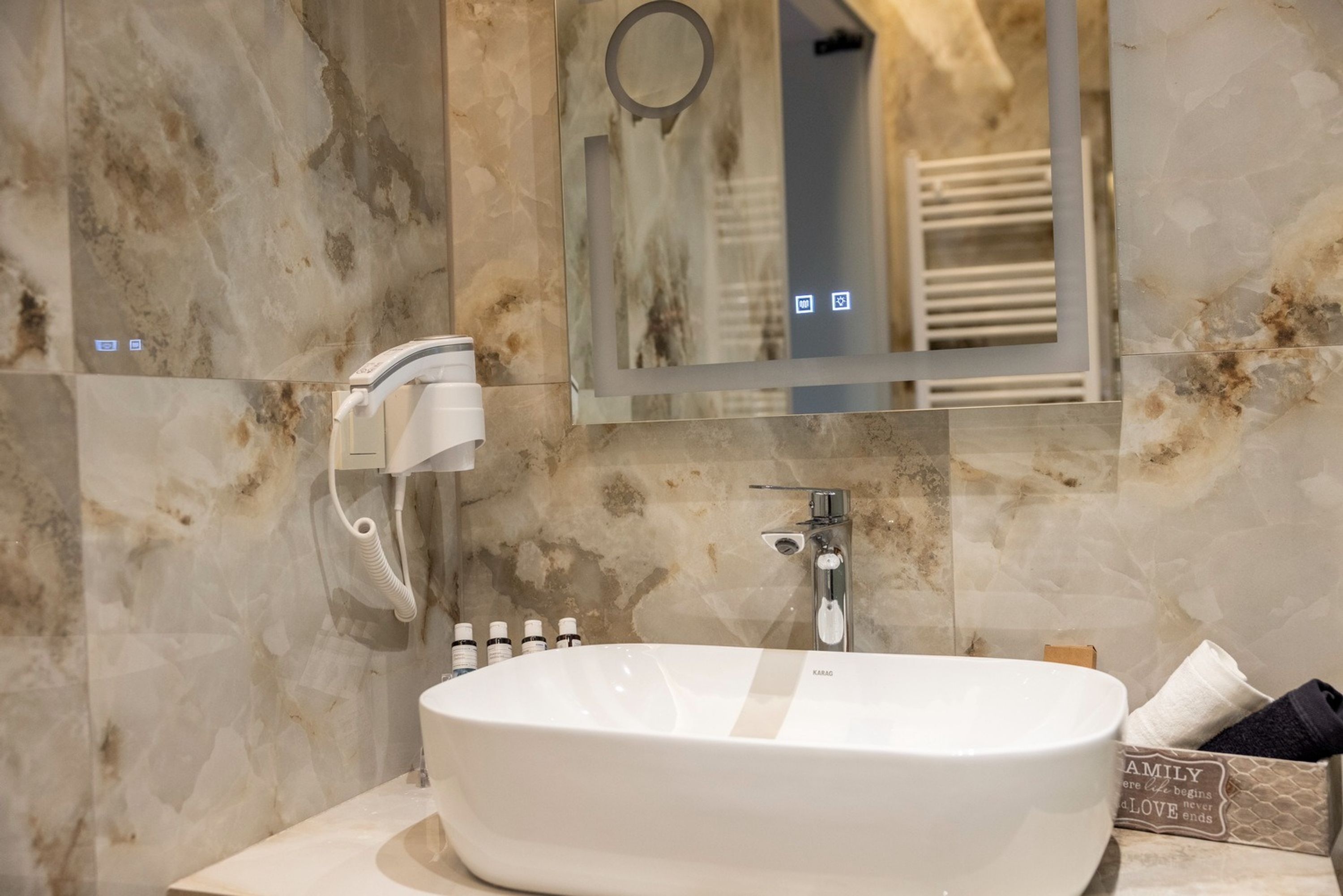 A bathroom with a large white sink, a handheld mirror, and a wall-mounted towel rack.