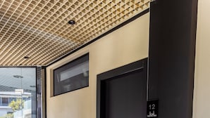 A modern hotel entrance with a black door, a bench, and a welcome mat.