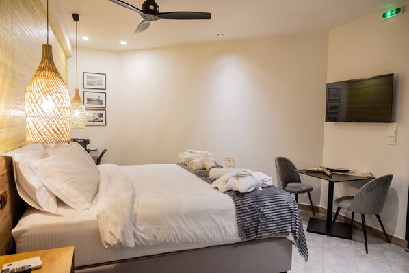 A hotel room with a bed, a desk, a chair, a television, and a hanging light fixture.